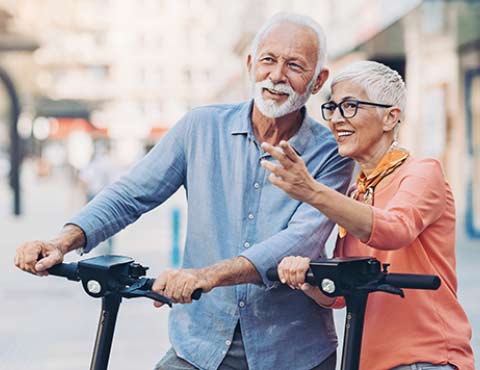 Retired couple enjoying riding scooters.